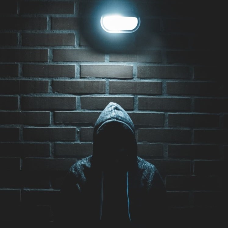 anonieme persoon blijft onder een lamp aan de bakstenen muur