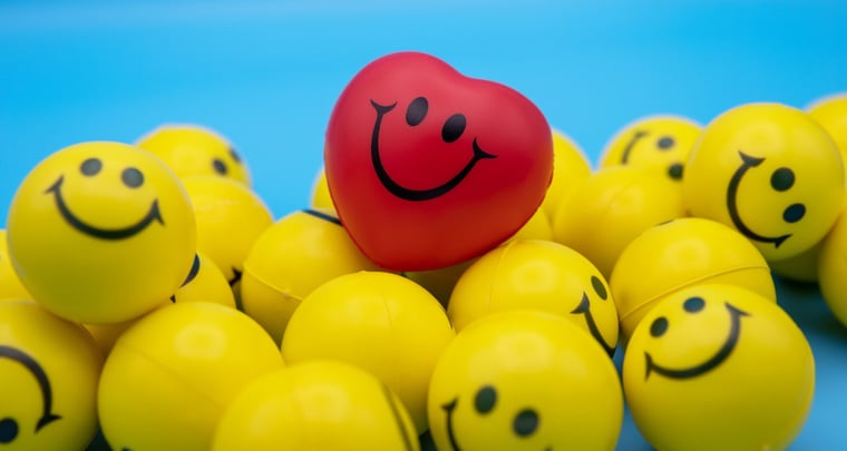 gele smiley emoji-ballen met bovenaan een rood smiley face emoji-hart